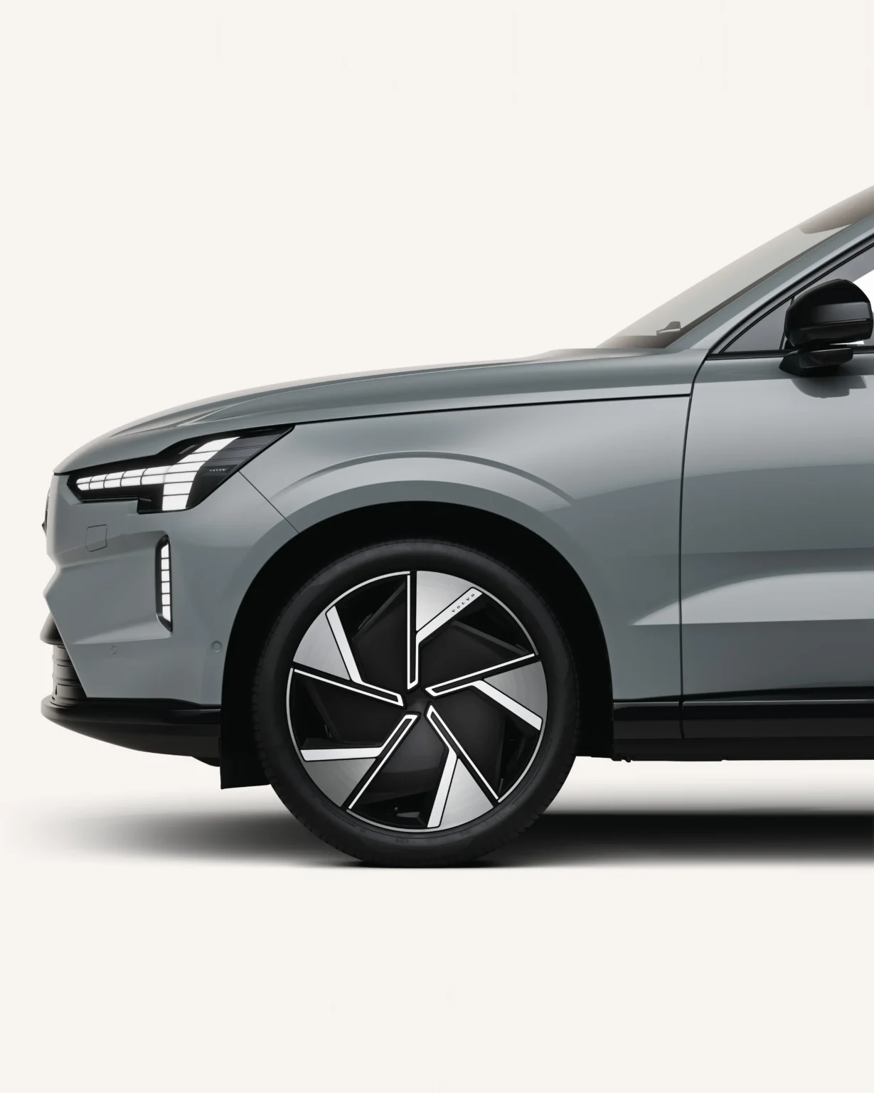 Front wheel and headlight of a grey Volvo EX90 in a white studio