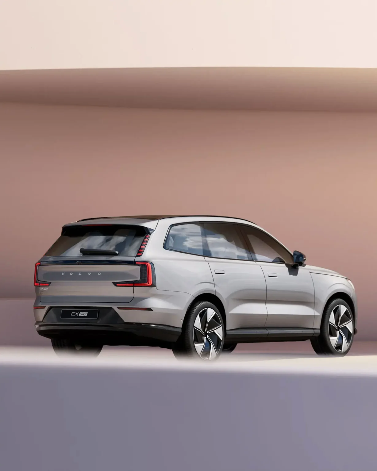 Pale grey Volvo EX90 from the rear three-quarter, showing its vertical tail lights