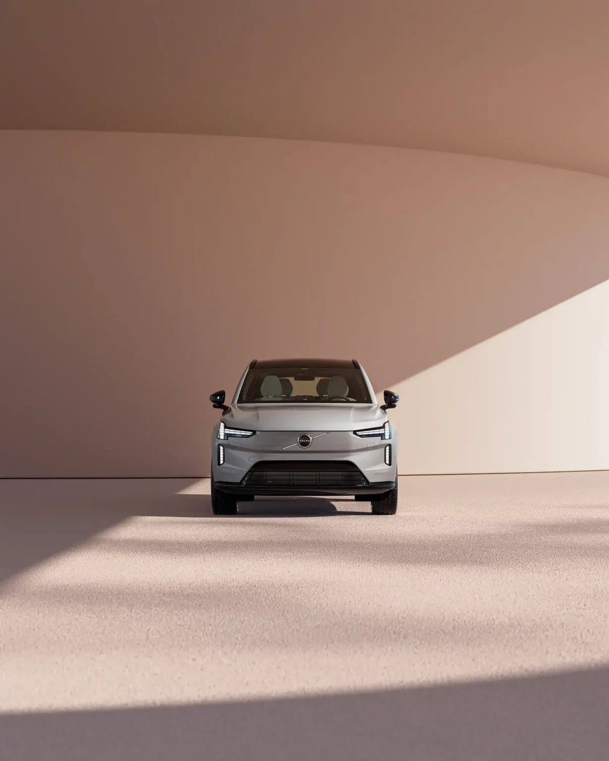 Volvo EX90 seen head-on in the shade of a curved wall