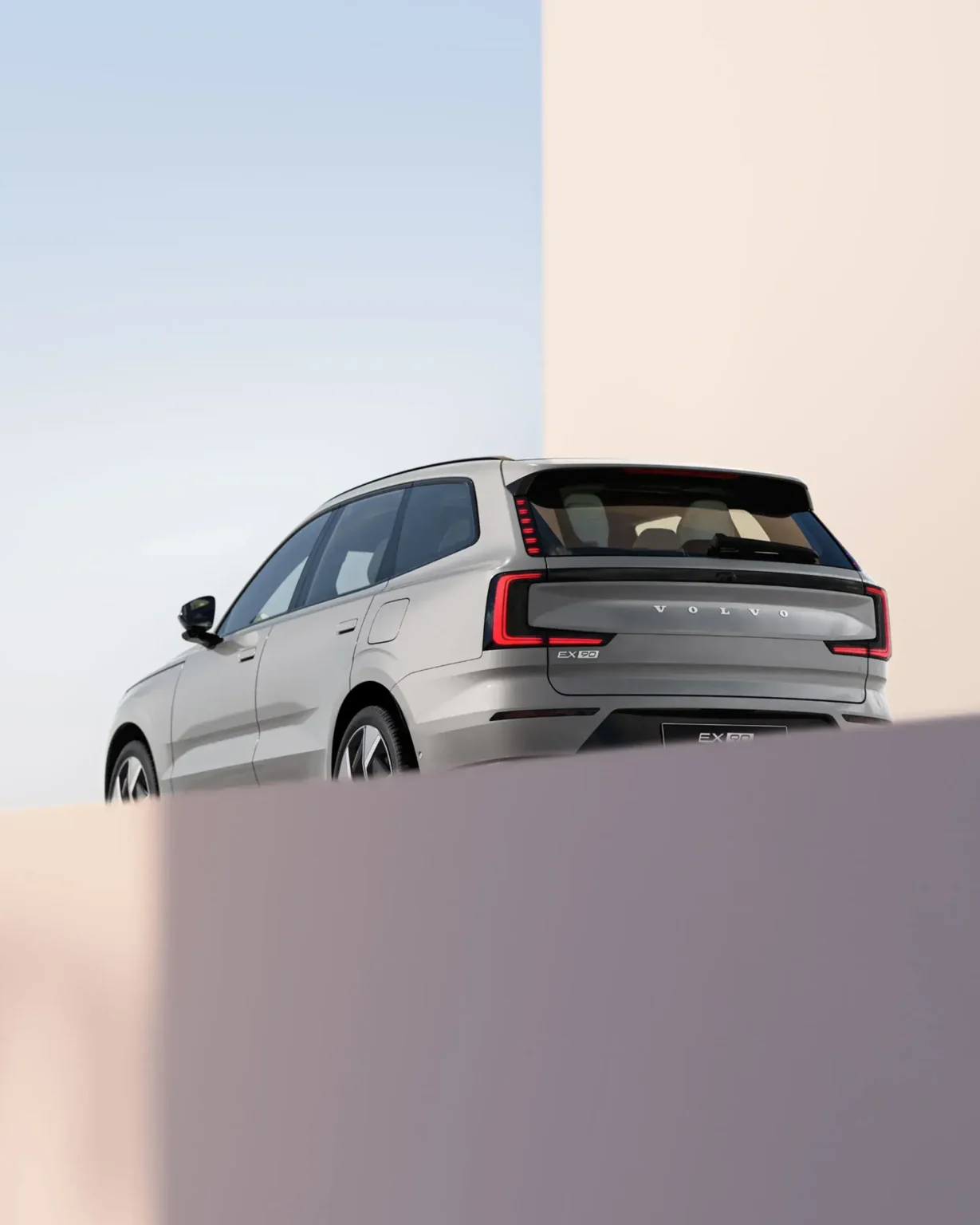 Low rear three-quarter view of the Volvo EX90 against a clear sky