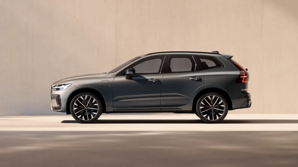 A grey Volvo SUV in profile in front of a sunlit beige wall