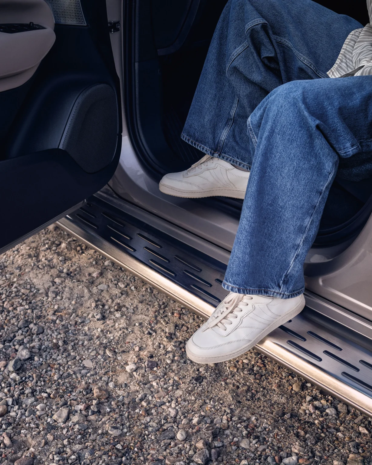 Someone in jeans stepping out of a Volvo XC90 onto its side running board
