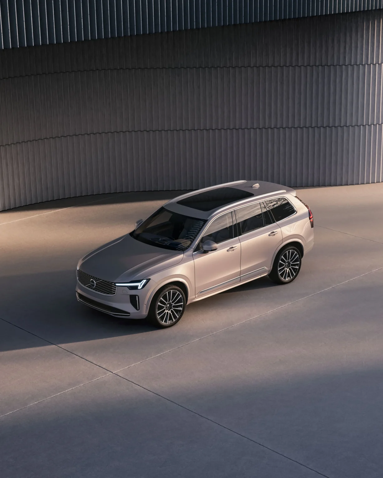 Volvo XC90 from a high front three-quarter angle beside a curved, ribbed wall