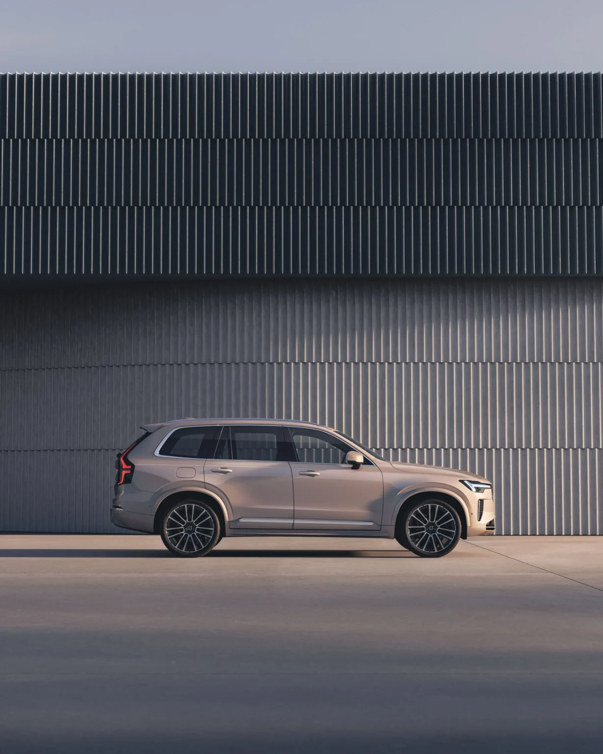 Side view of a Volvo XC90 parked beside a curved, ribbed concrete wall