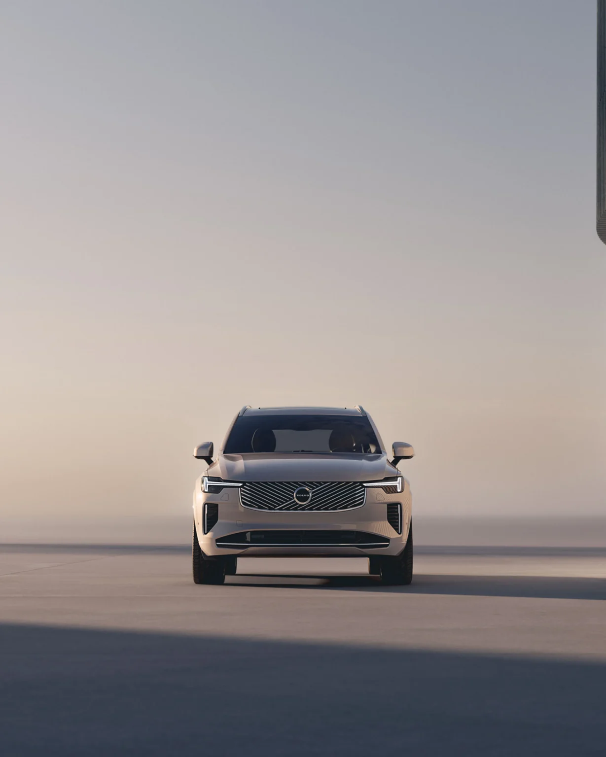 Volvo XC90 from the front, parked by a curved concrete wall at dusk