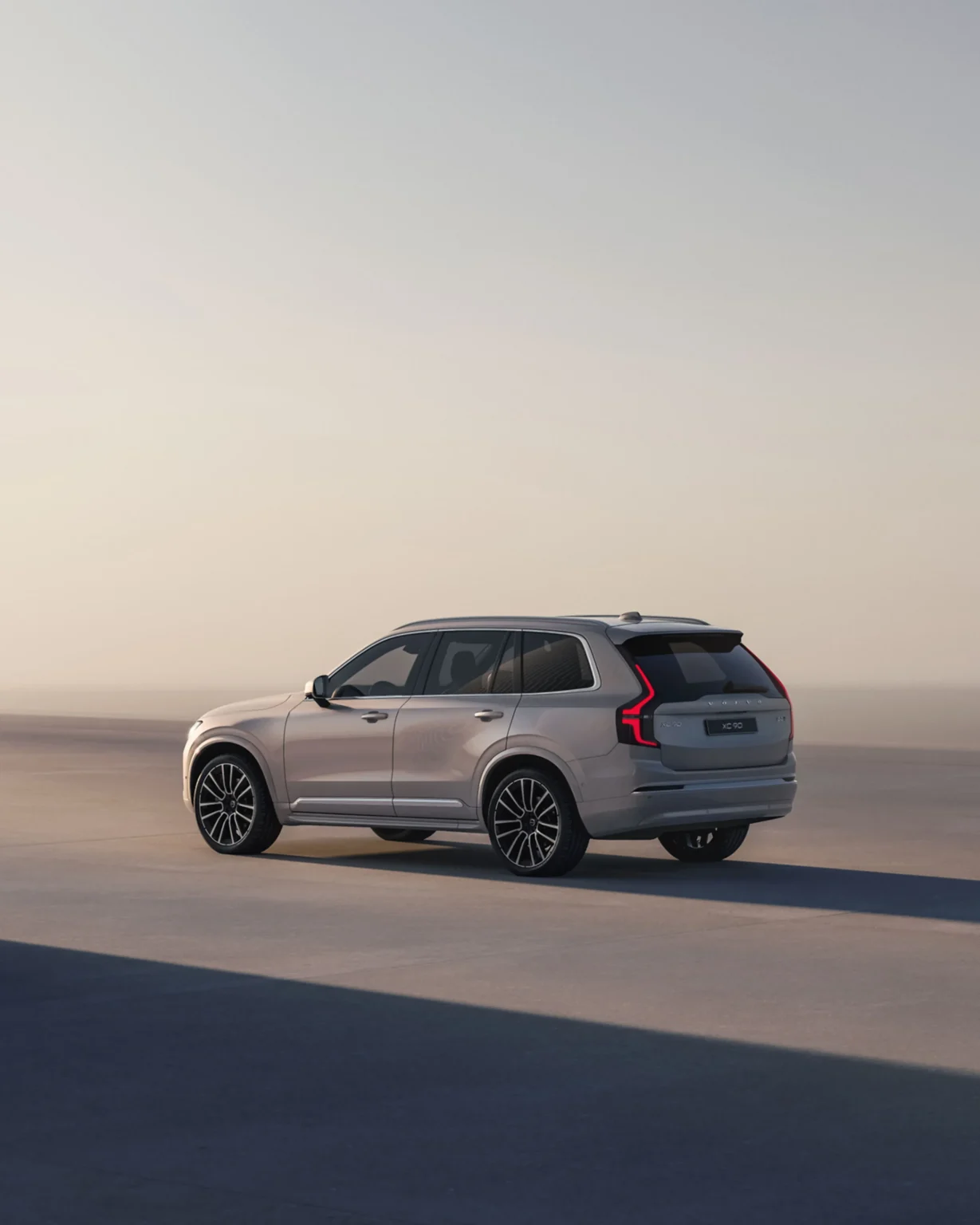 Volvo XC90 from the rear three-quarter in a sunlit concrete courtyard