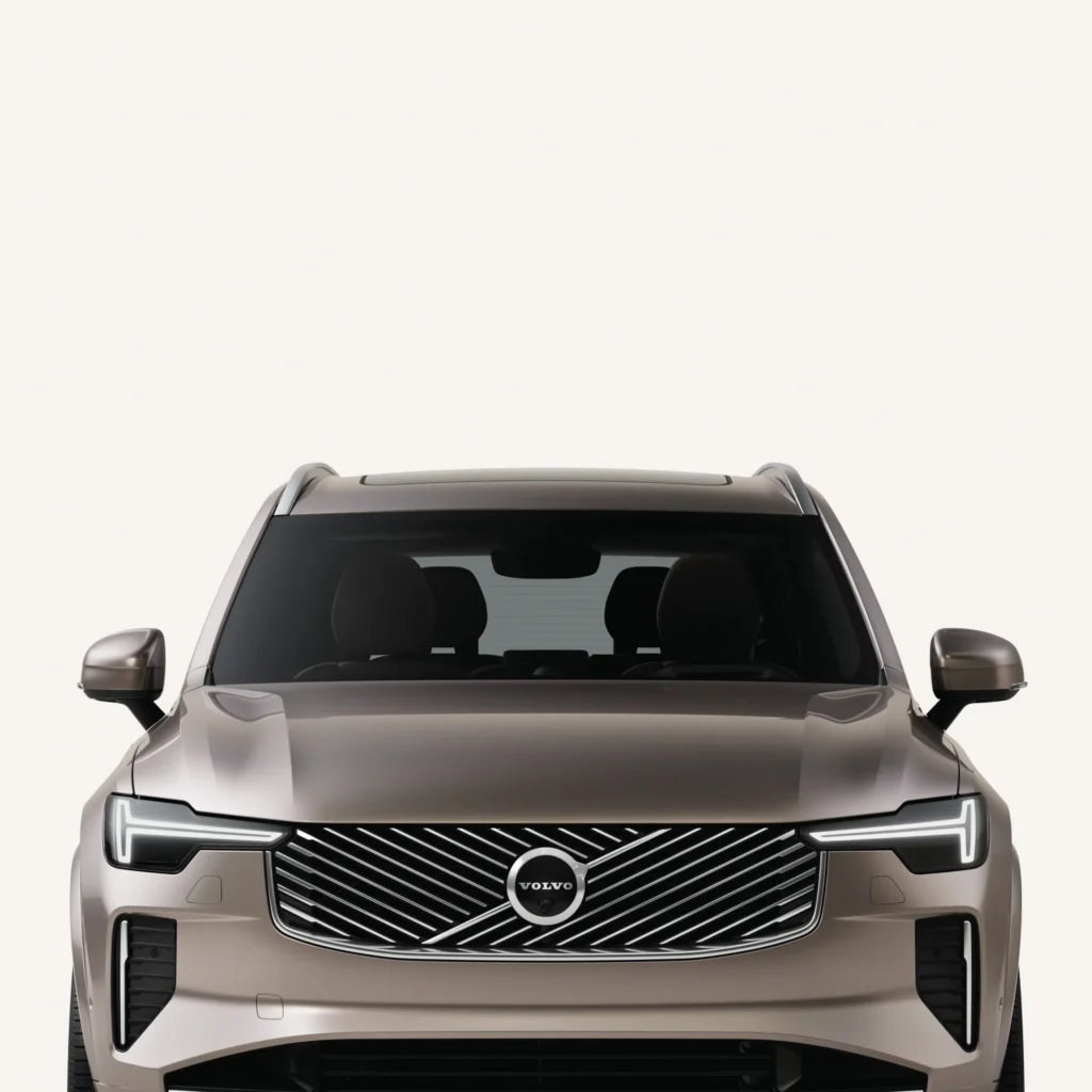 Front of a Volvo XC90 against a pale studio background, showing its grille and slim LED headlights