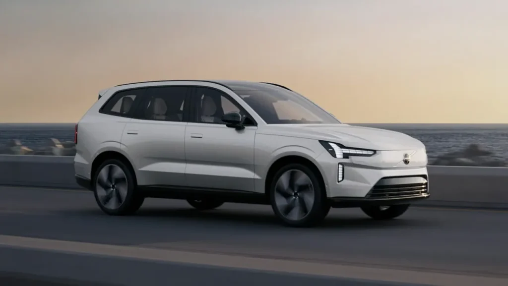 Volvo EX90 in Crystal White on a seafront road at dusk