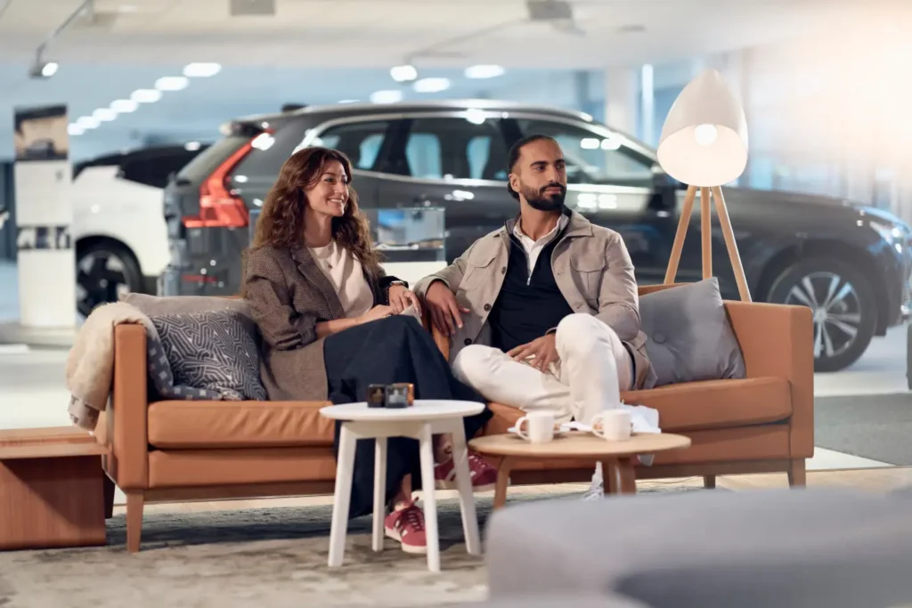 A man and a woman relaxing on a sofa with coffee in a Volvo showroom lounge