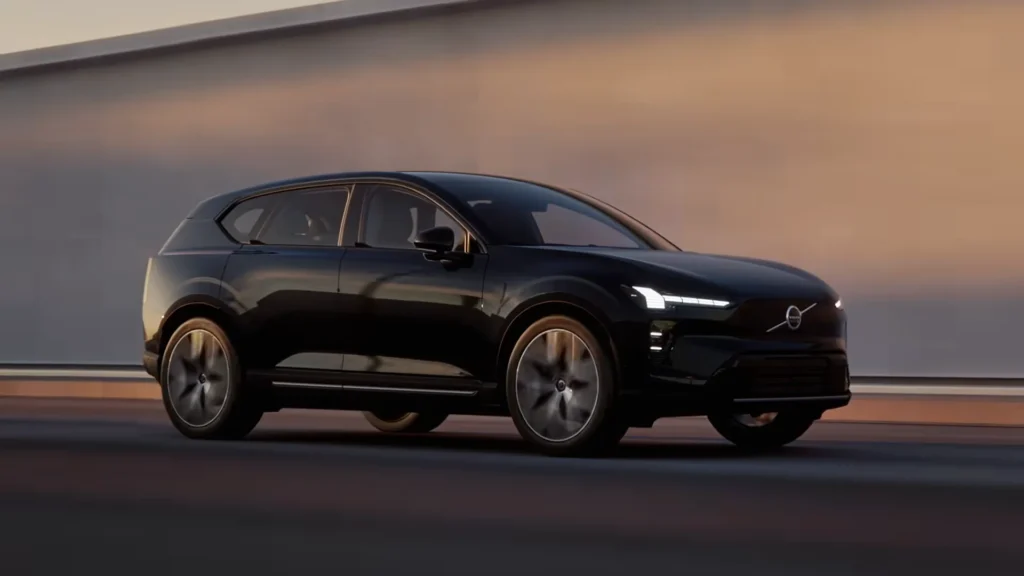 Volvo EX60 in Onyx Black driving past a wall at dusk