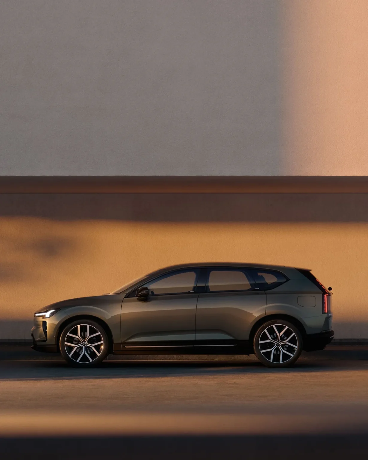 Side view of a Volvo EX60 beside a wall at dusk