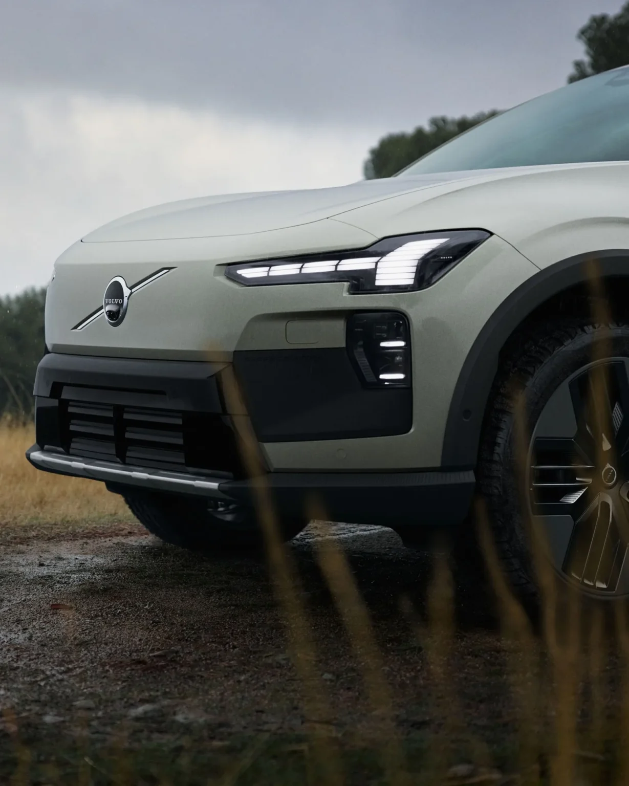 Front of a Volvo EX60 Cross Country parked on grass in woodland