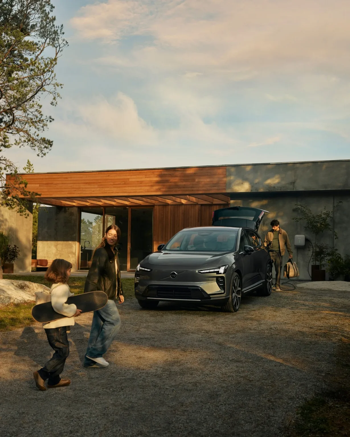 Family walking towards a Volvo EX60 parked outside a modern house