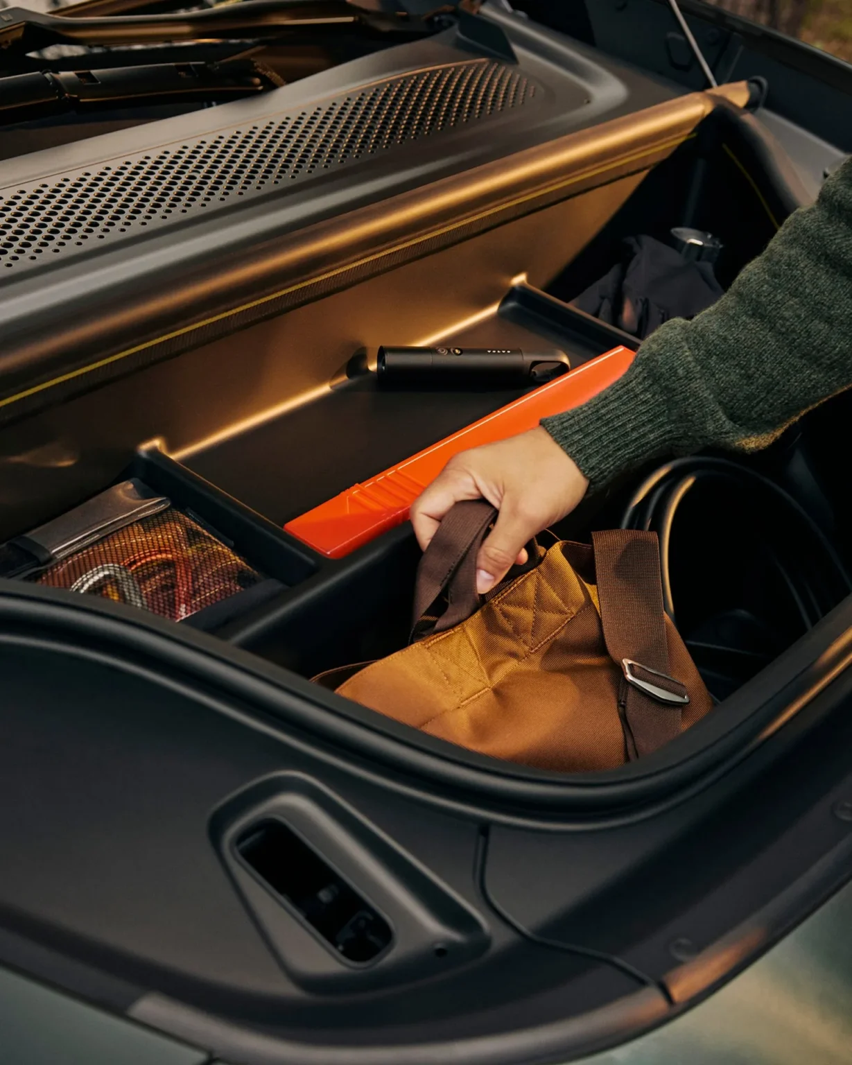 Person placing a bag in the front load compartment of a Volvo EX60