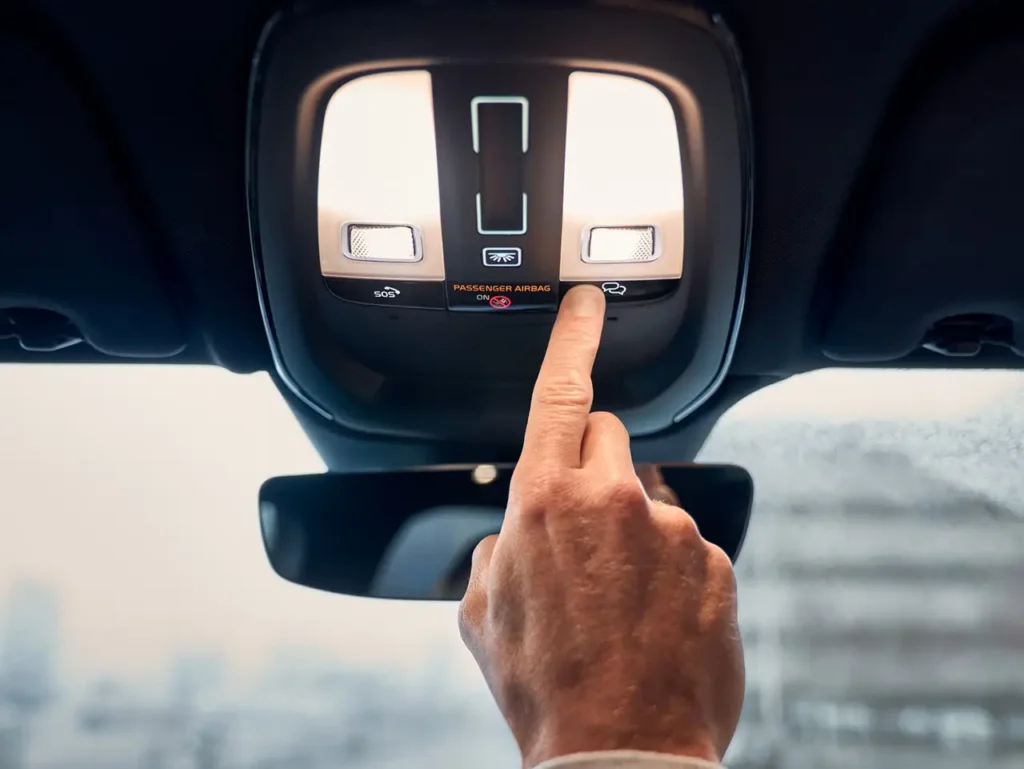 A finger pressing a button on the overhead console of a Volvo