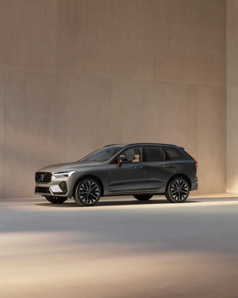 A dark grey Volvo XC60 parked in front of a warm beige wall in soft, low sunlight