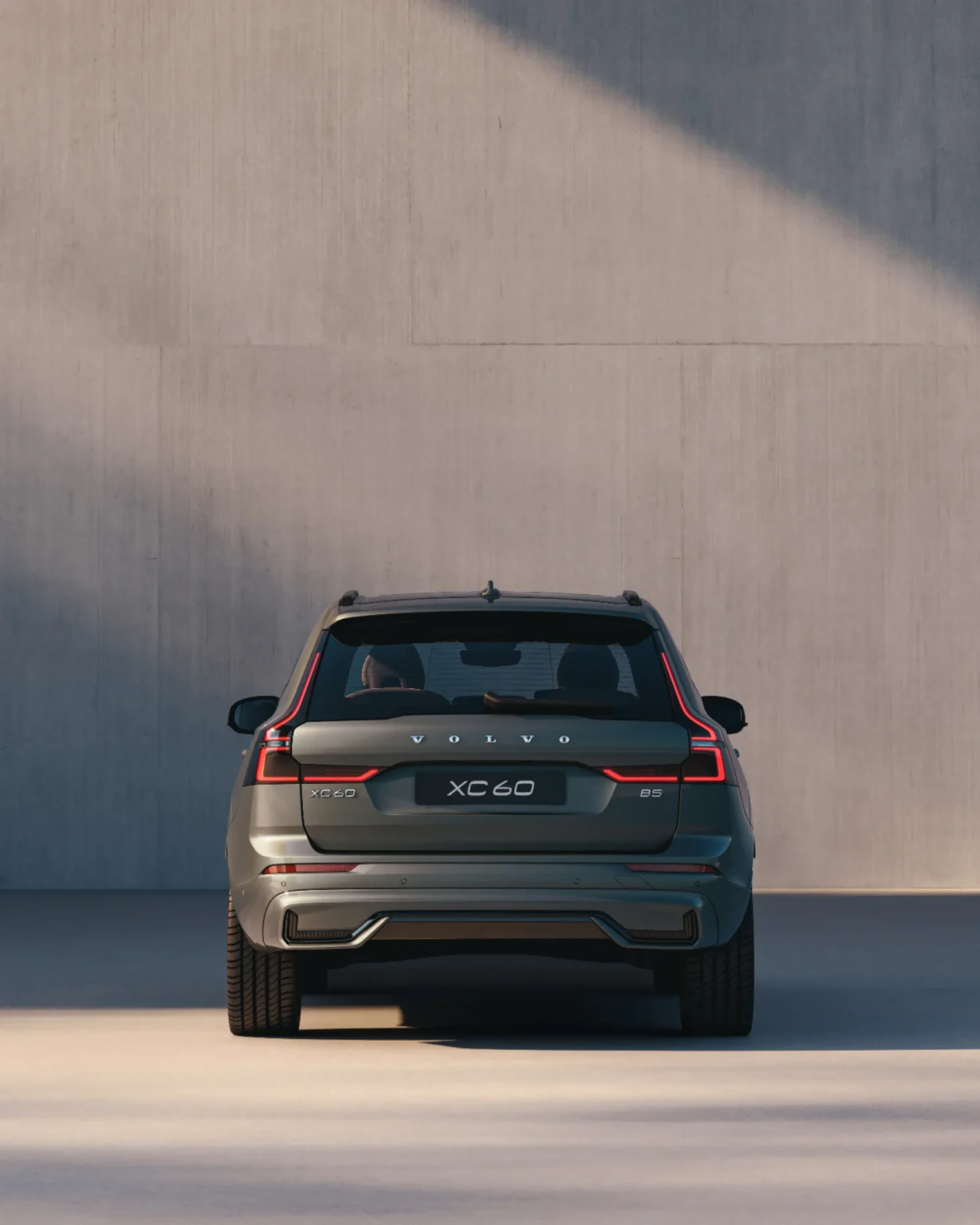 Volvo XC60 from behind, parked against a tall concrete wall