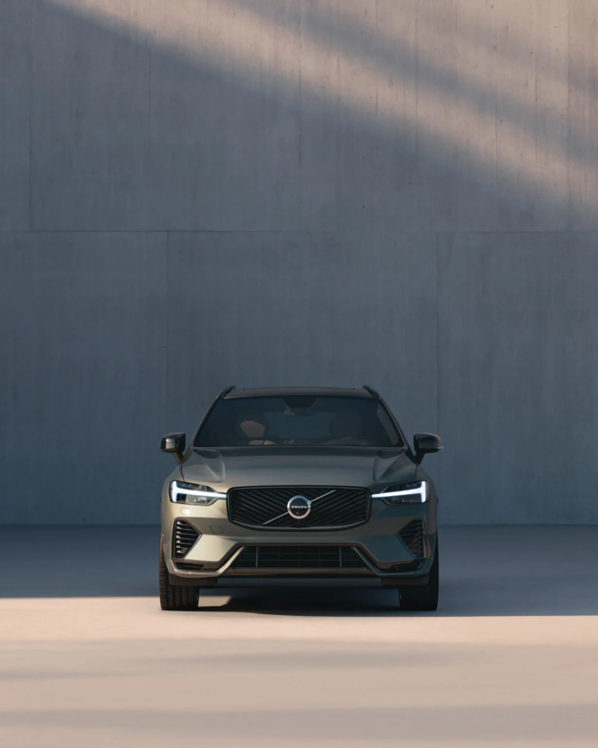 Volvo XC60 from the front, parked against a tall concrete wall