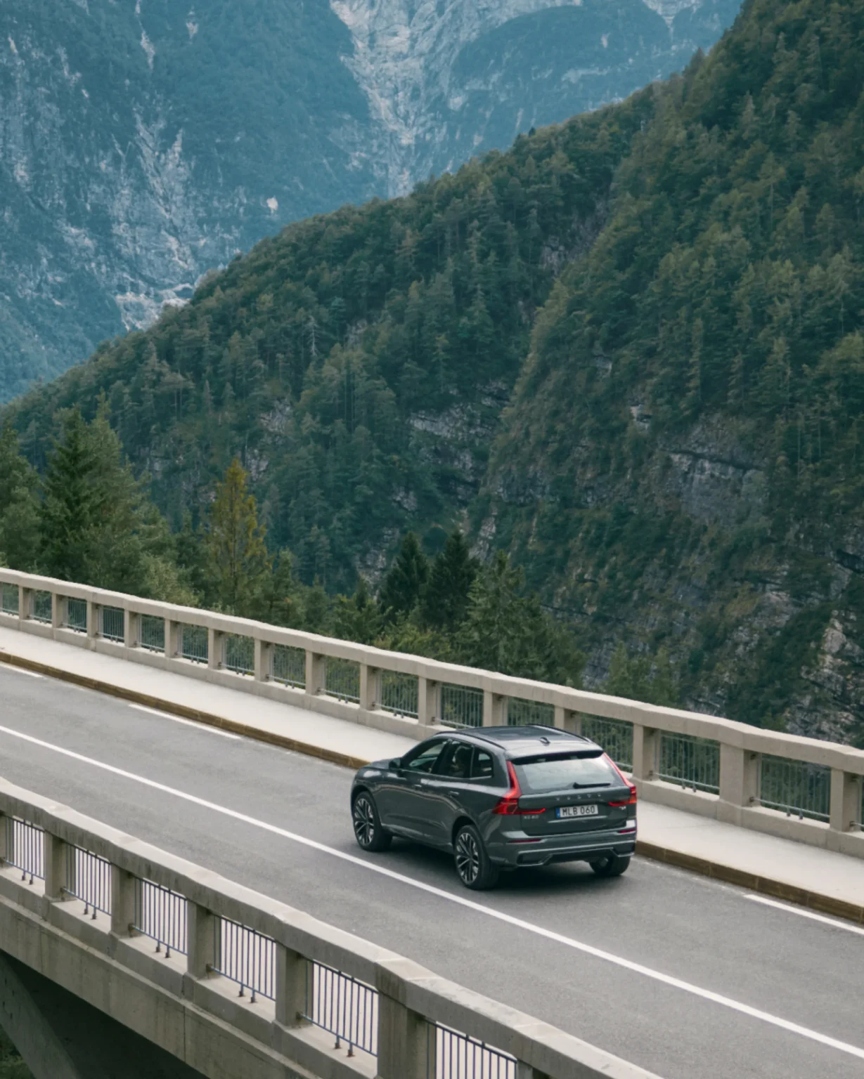 Volvo XC60 driving across a high bridge with forested mountains behind