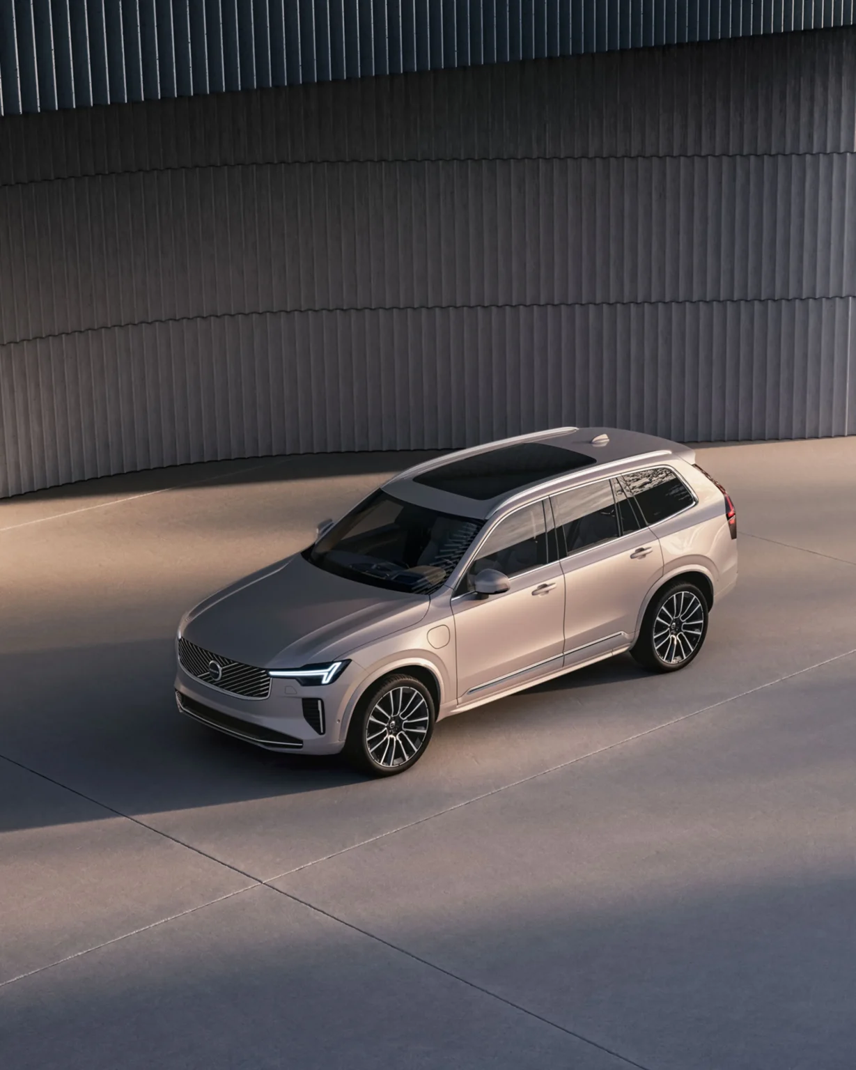 Volvo XC90 from a high front three-quarter angle beside a curved, ribbed wall